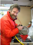 Photo of a scientist washing a bongo sample into a sample jar.