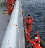 Image of scientists and crew climbing down a jacobs ladder to a waiting zodiac.