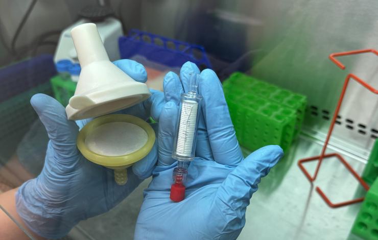 Scientist with gloves holdering a smith-root filter and sterivex filter
