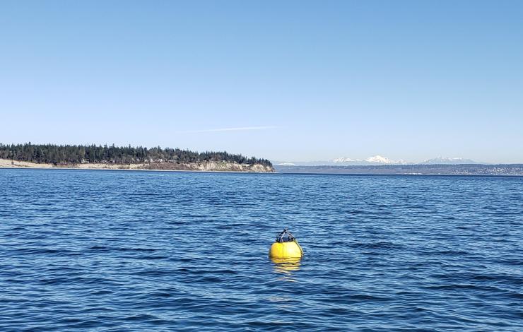 Yellow surface buoy floating in the water during testing of the first flotation controllable ocean mooring system