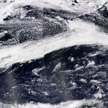 Satellite image stitched together showing the Pacific Ocean with an atmospheric river (shown as a river of white cloud cover) across the North Pacific Ocean