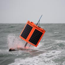 Orange autonomous vehiclewith a square wing in stormy water conditions 