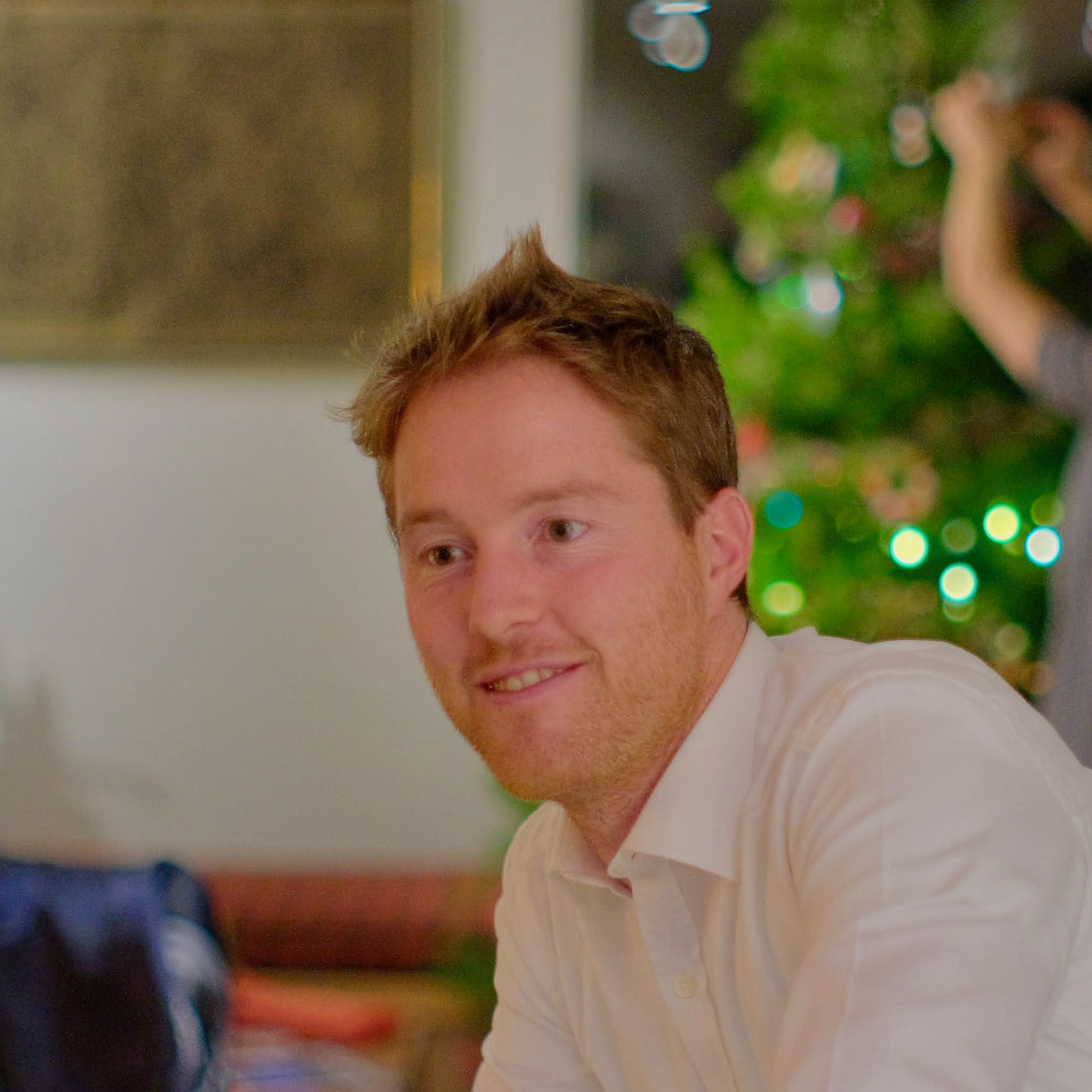 Yann looking to the side of the camera wearing a white collared shirt